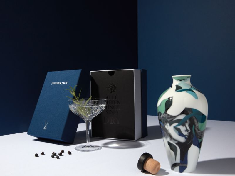 MEISSEN-Vase der JUNIPER JACK Art Edition als Ginflasche, daneben ein Glas Gin und Wacholderbeeren
