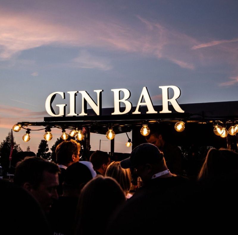 Beleuchtetes GIN-BAR-Schild der Tipsy Horse Bar in der Dämmerung mit Gästen